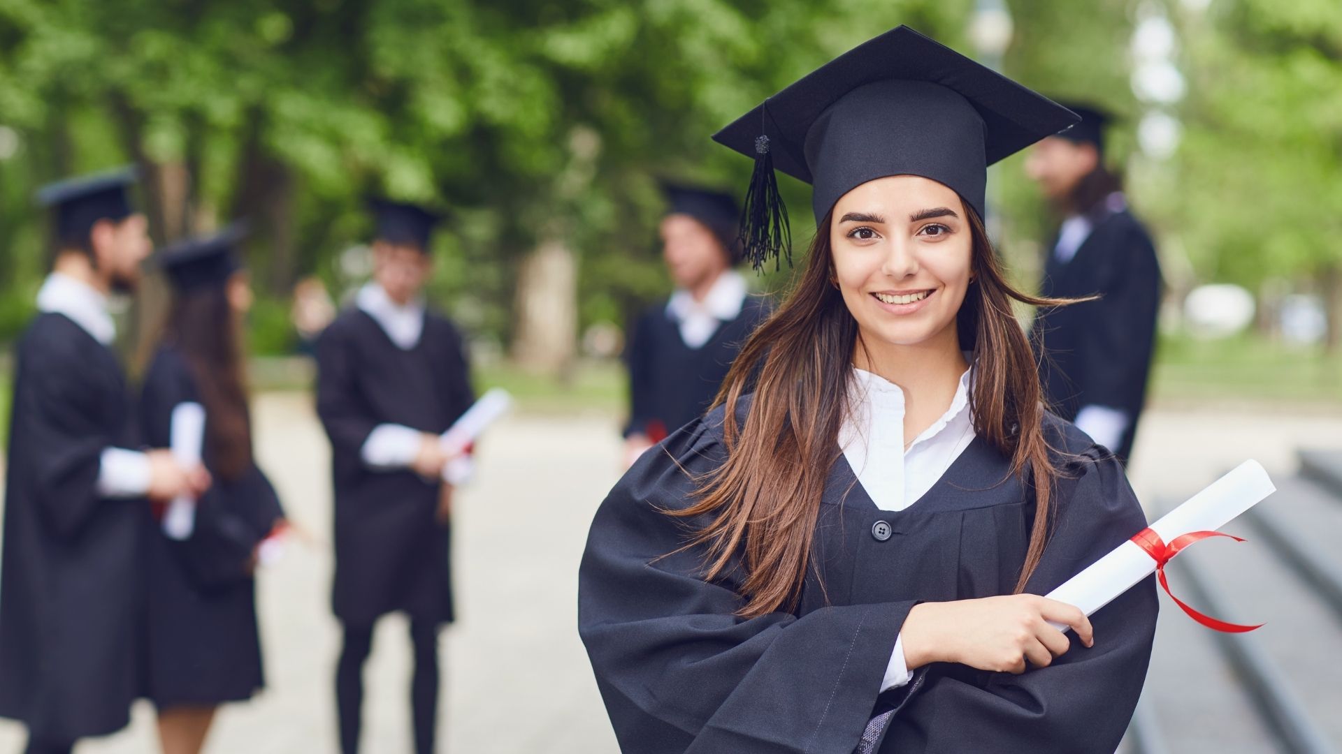 A student holding her diploma standing alongside other graduates.